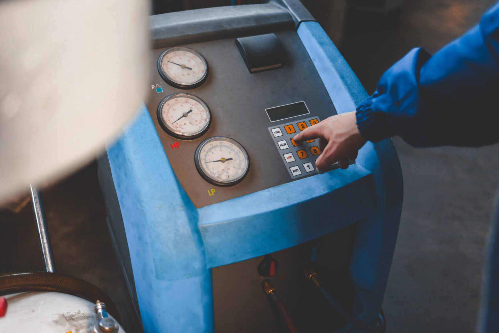 Technicien utilisant une machine de récupération de fréon HVAC avec manomètres et clavier numérique